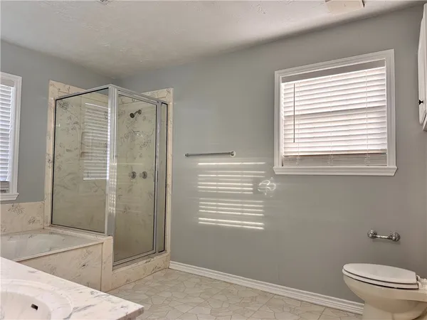 a bathroom with a granite countertop toilet a sink and shower