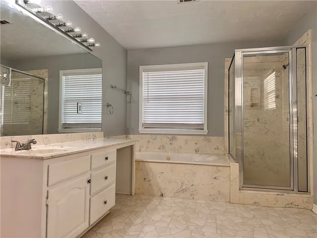 a bathroom with a granite countertop sink a large mirror and a bathtub