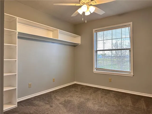 an empty room with a chandelier fan and windows