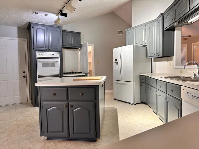 a kitchen with stainless steel appliances granite countertop a refrigerator a stove and a sink