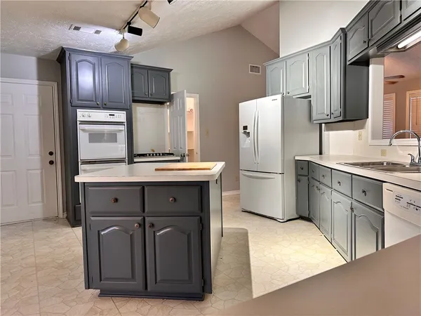 a kitchen with stainless steel appliances granite countertop a refrigerator a stove and a sink