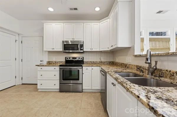 a kitchen with granite countertop white cabinets stainless steel appliances and a sink