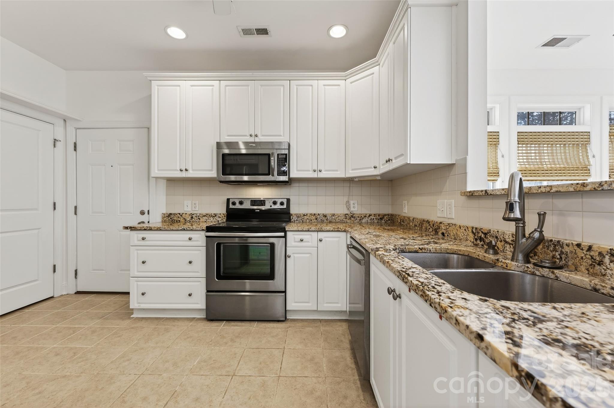 2803 Bellasera Way Matthews, NC 28105 - Photo 14 of 27 a kitchen with granite countertop a sink a stove and cabinets