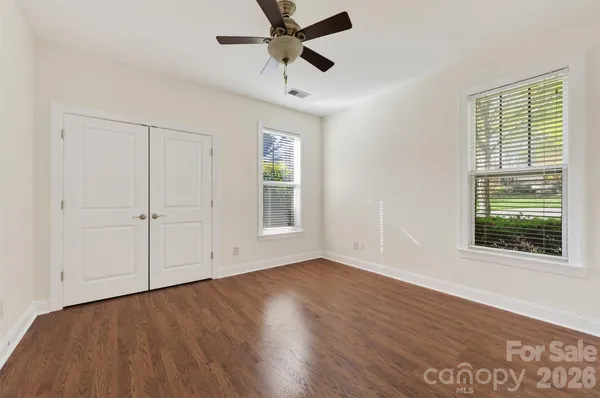 an empty room with wooden floor and ceiling fan