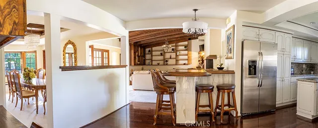 a kitchen with stainless steel appliances kitchen island granite countertop a refrigerator a stove and a dining table with wooden floor