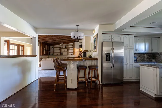 a kitchen with stainless steel appliances a dining table chairs and wooden floor