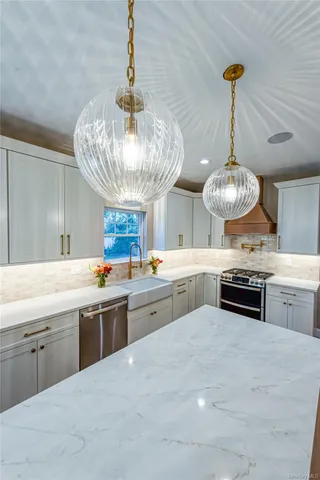 a kitchen with stainless steel appliances a chandelier and a view of living room
