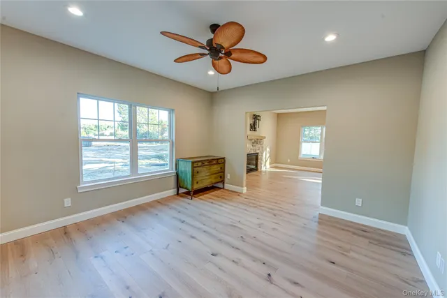 a view of an empty room with window and wooden floor
