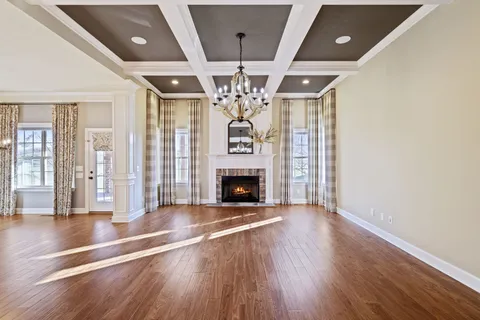 a view of an empty room with wooden floor fireplace and a window