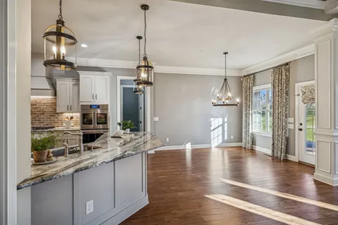 a kitchen with stainless steel appliances granite countertop a sink a stove and a wooden floor