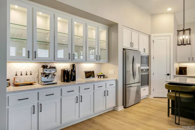 a kitchen with granite countertop a refrigerator a sink a stove and white cabinets