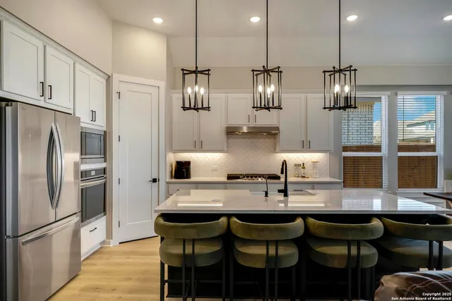 a kitchen with stainless steel appliances granite countertop a kitchen island hardwood floor and chairs