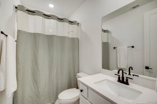 a bathroom with a sink a toilet a mirror and shower curtain