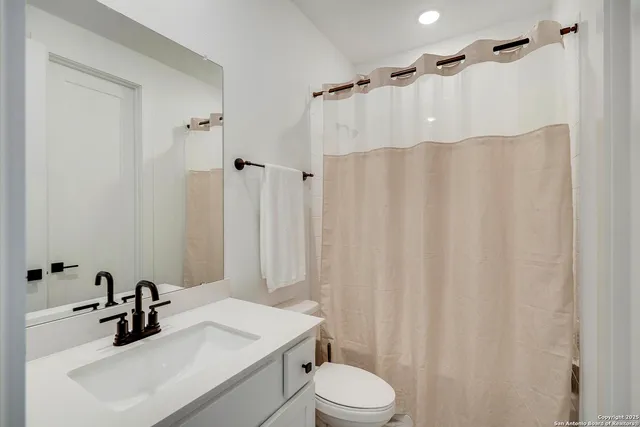a bathroom with a sink a toilet and shower curtain