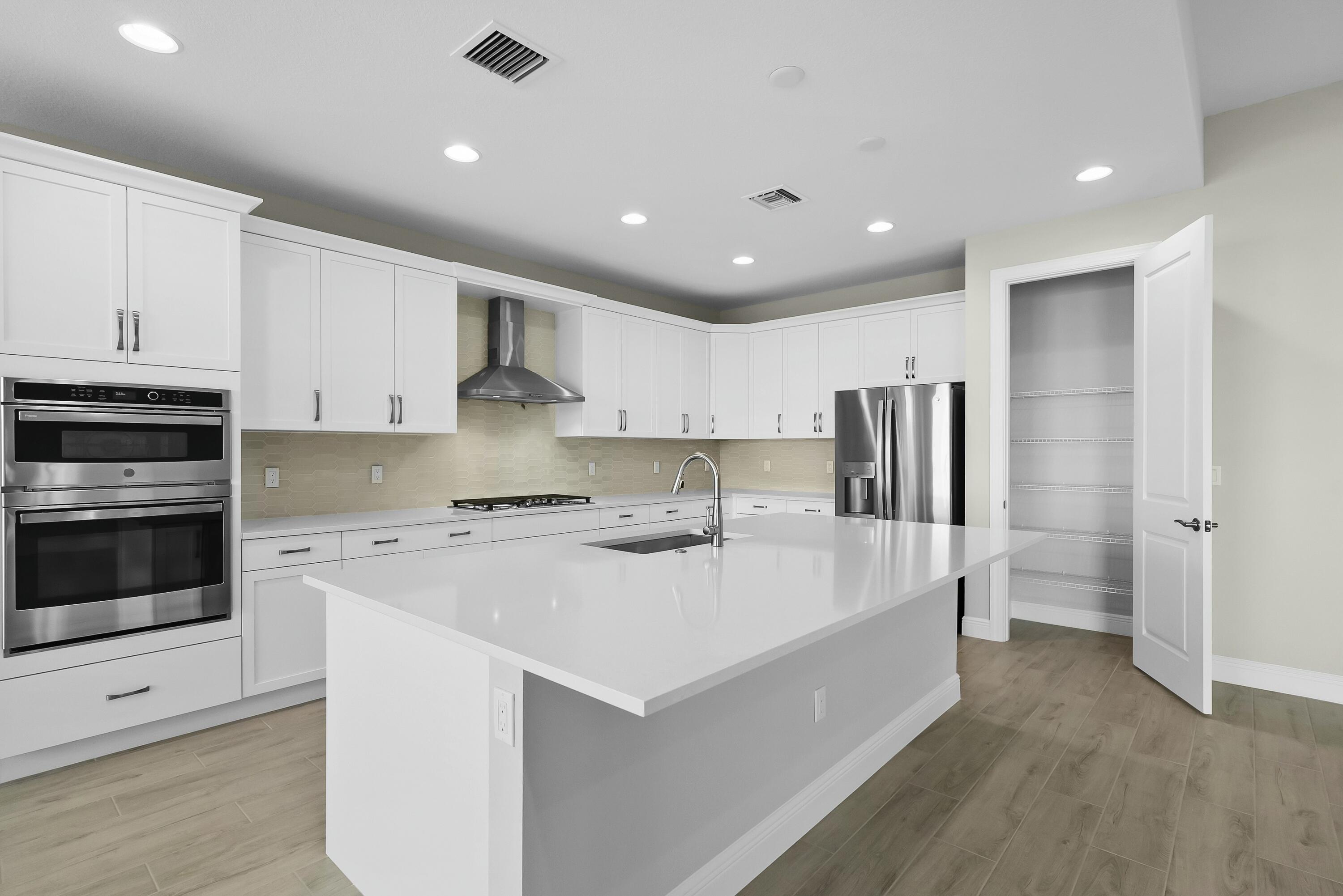 6382 High Pointe Circle Vero Beach, FL 32967 - Photo 24 of 55 a large white kitchen with a stove a sink a refrigerator and cabinets