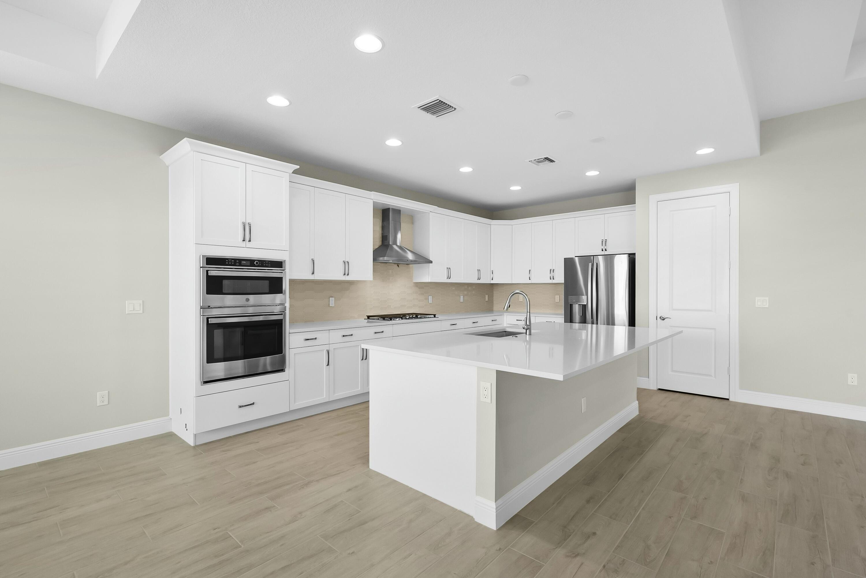 6382 High Pointe Circle Vero Beach, FL 32967 - Photo 25 of 55 a large white kitchen with stainless steel appliances and white cabinets