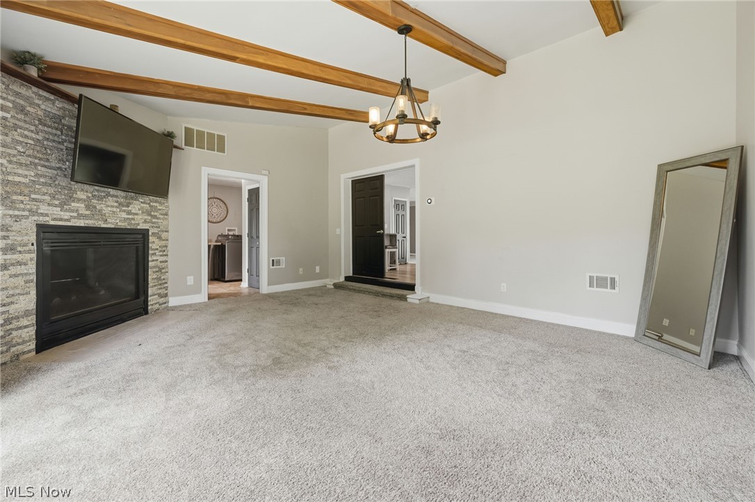 8160 Joyce Road Broadview Heights, OH 44147 - Photo 21 of 45 Spacious living area featuring vaulted ceilings with exposed wood beams, a stacked stone fireplace, and light gray wall paint
