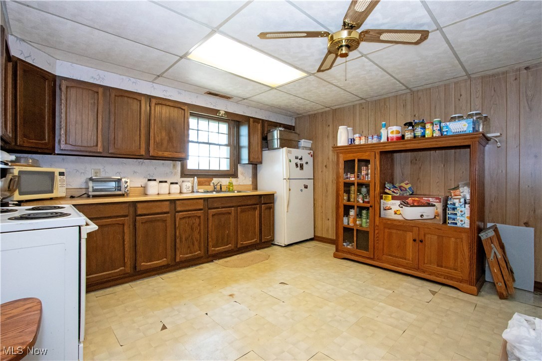 1292 Cinder Road Southeast Carrollton, OH 44615 - Photo 37 of 42 Kitchen featuring white appliances, wood walls, light floors, light countertops, and a ceiling fan