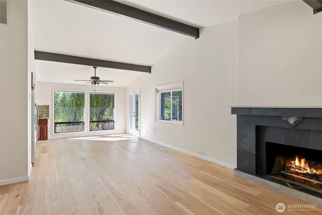 a view of an empty room with wooden floor fireplace and a window