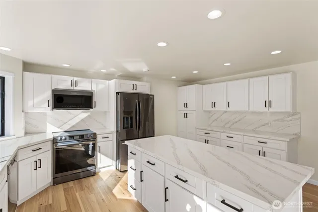 a kitchen with stainless steel appliances kitchen island granite countertop a stove a sink and a refrigerator
