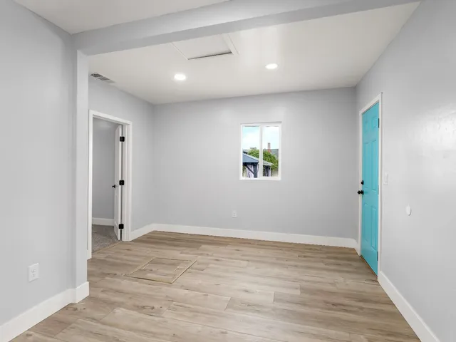 a view of an empty room with wooden floor and a window