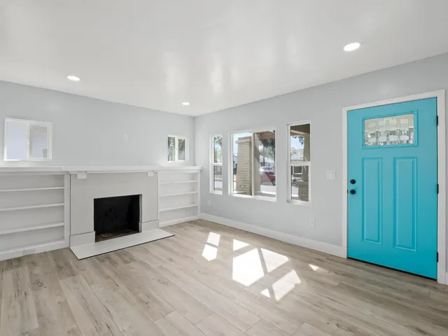 an empty room with windows and fireplace