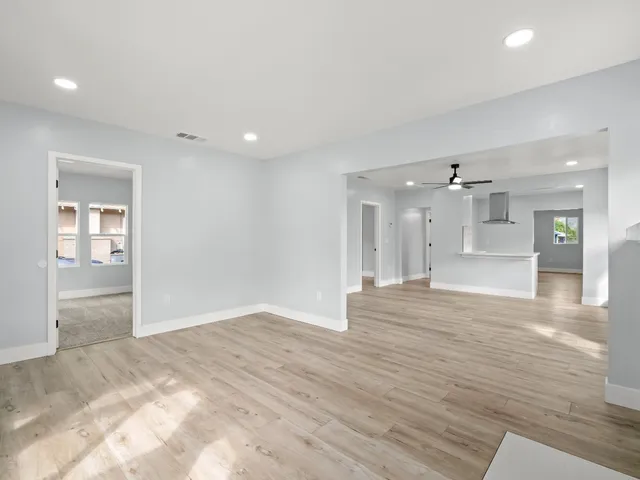a view of a hallway with wooden floor and a kitchen