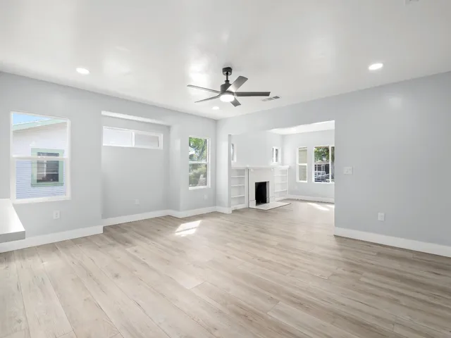 a view of an empty room with a window and a kitchen