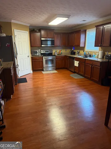 a kitchen with stainless steel appliances granite countertop a sink counter space cabinets and wooden floor
