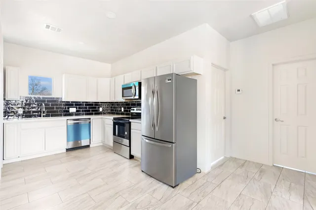 a kitchen with granite countertop a refrigerator and a stove top oven