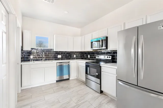 a kitchen with granite countertop white cabinets and stainless steel appliances