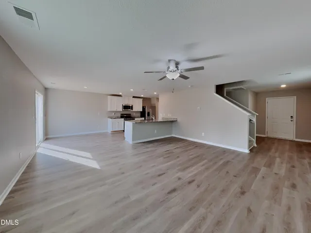 a view of a livingroom with wooden floor and a ceiling fan