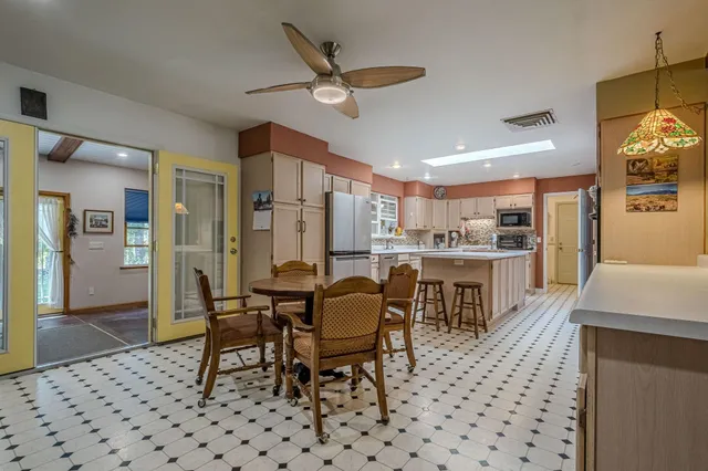 a dining hall with stainless steel appliances a dining table and chairs