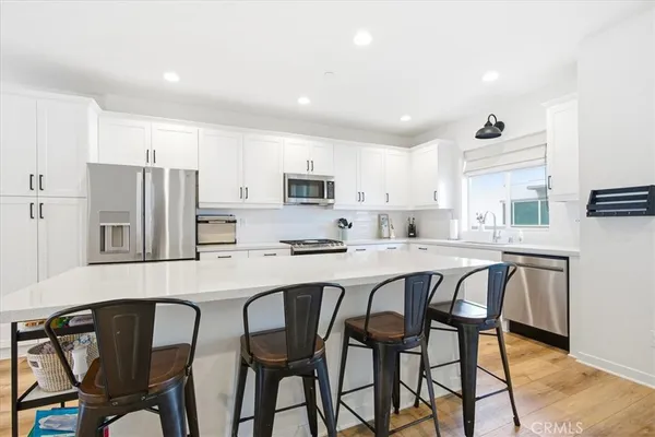 a kitchen with stainless steel appliances granite countertop a table chairs refrigerator and microwave