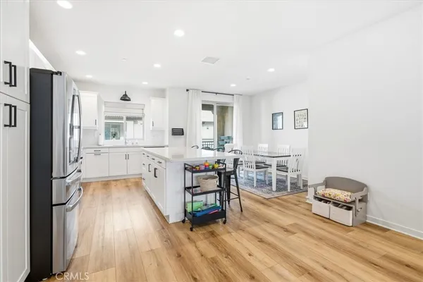 a large living room with stainless steel appliances a couch and a dining table with wooden floor