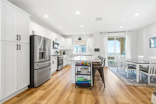 a kitchen with stainless steel appliances granite countertop a refrigerator oven a stove a dining table and chairs with wooden floor