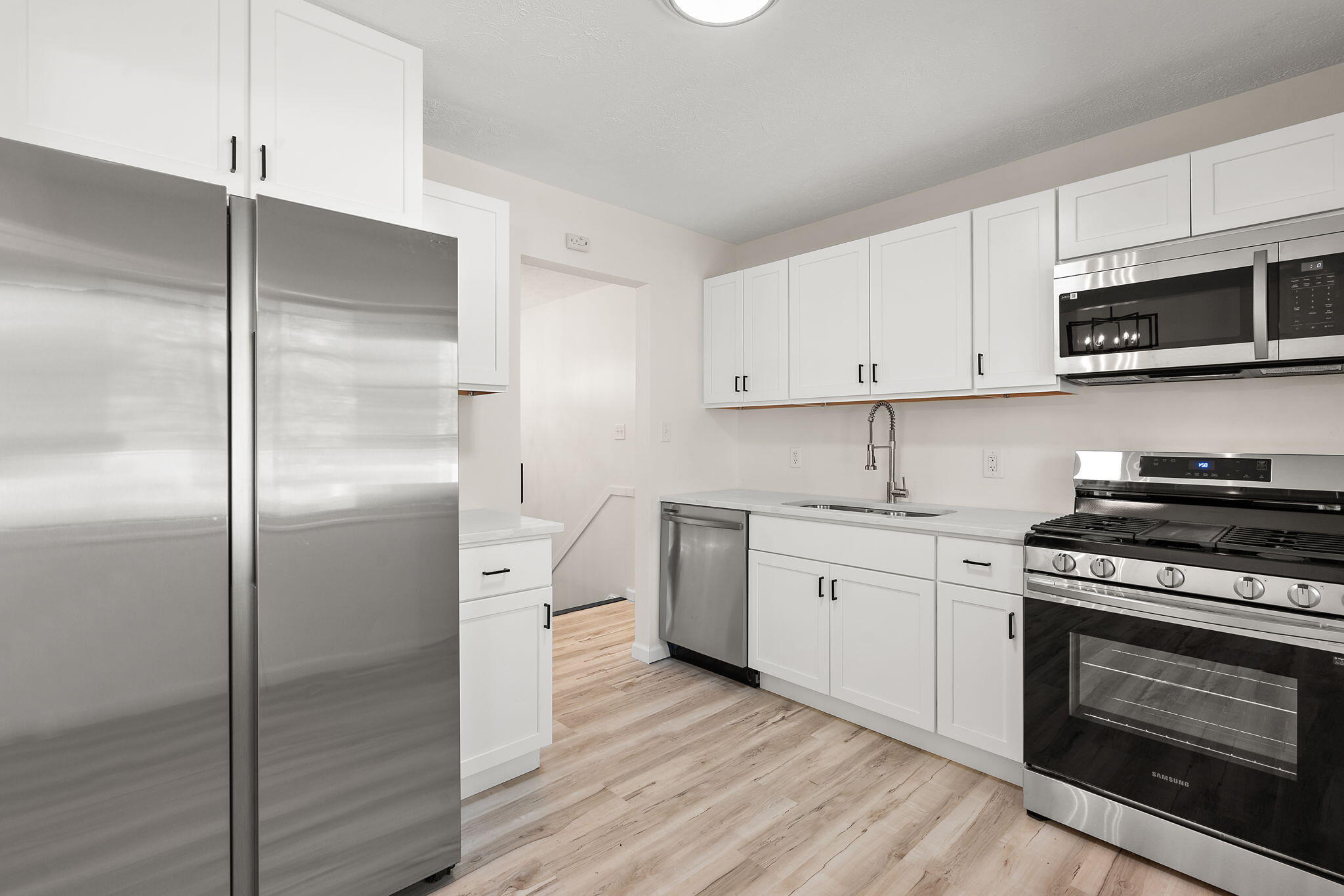 654 Cheyenne Drive Lowell, IN 46356 - Photo 4 of 11 a kitchen with cabinets stainless steel appliances and wooden floor