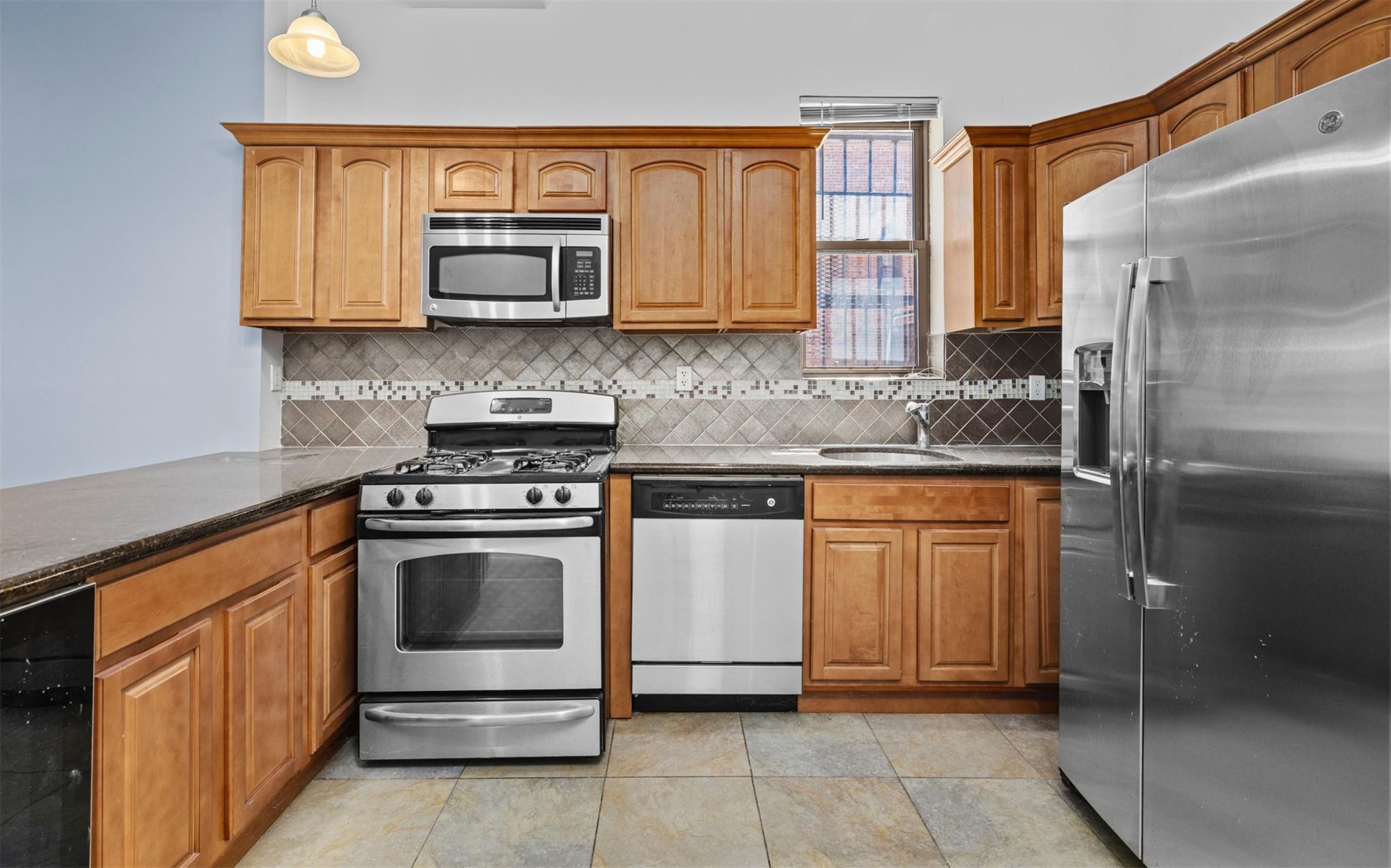 626 Madison Street Brooklyn, NY 11221 - Photo 16 of 42 Kitchen with appliances with stainless steel finishes, a sink, beverage cooler, tasteful backsplash, and brown cabinets
