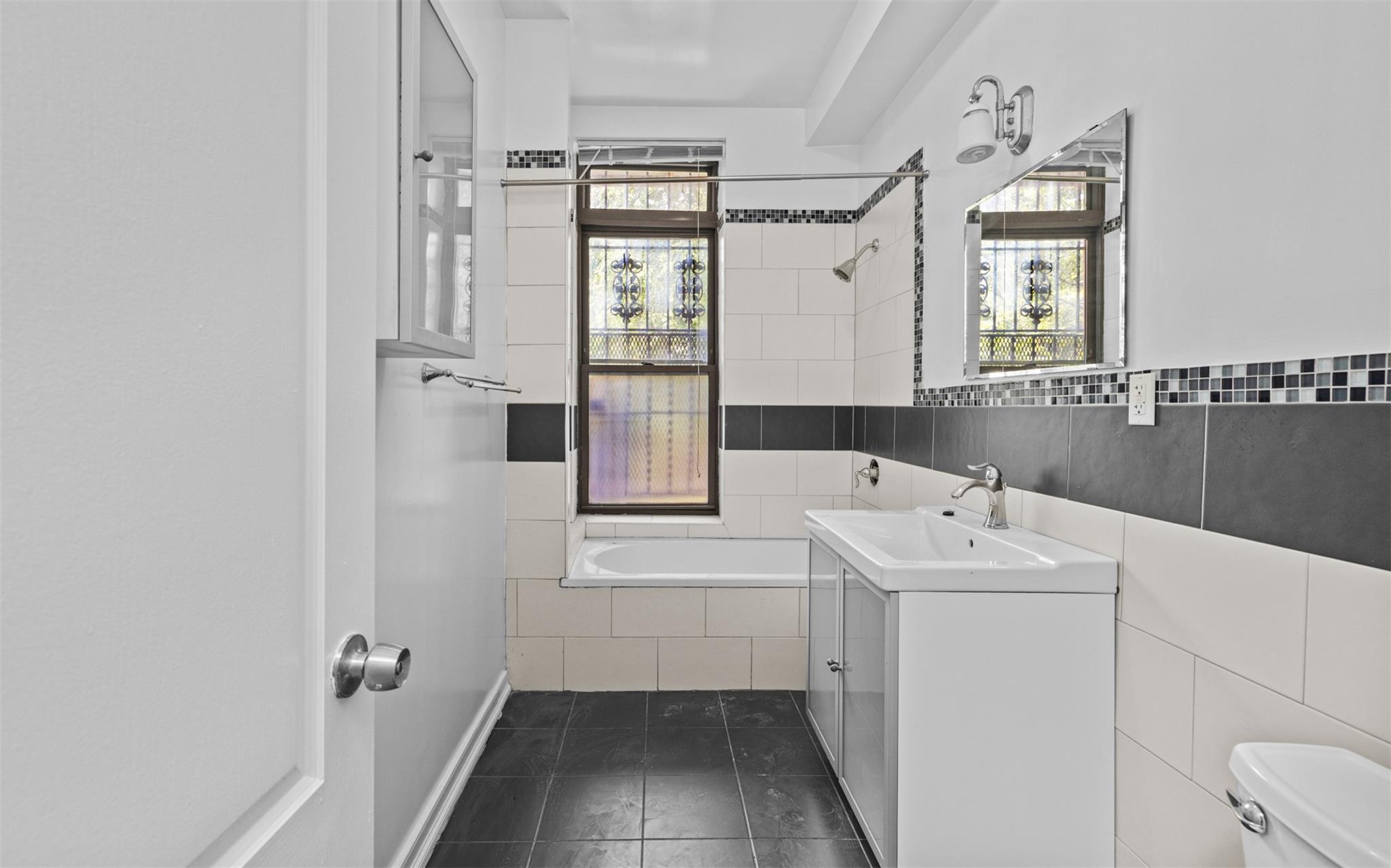 626 Madison Street Brooklyn, NY 11221 - Photo 19 of 42 Full bathroom with healthy amount of natural light, toilet, tile walls, vanity, and tile patterned flooring