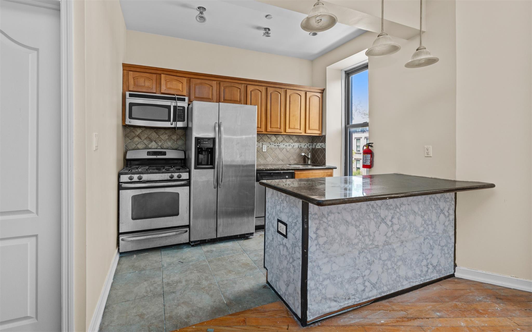 626 Madison Street Brooklyn, NY 11221 - Photo 22 of 42 Kitchen with appliances with stainless steel finishes, dark countertops, tasteful backsplash, baseboards, and a peninsula
