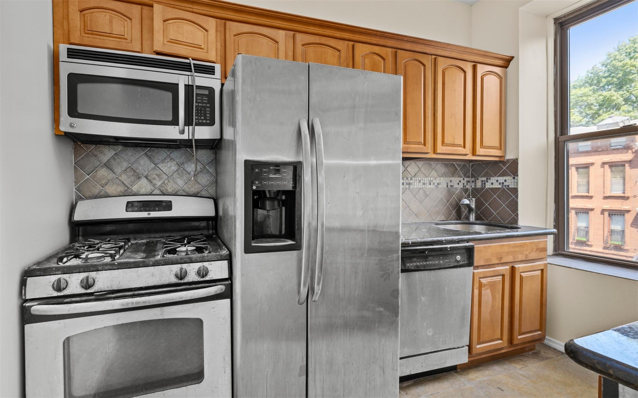 626 Madison Street Brooklyn, NY 11221 - Photo 23 of 42 Kitchen featuring appliances with stainless steel finishes, tasteful backsplash, baseboards, a sink, and brown cabinets