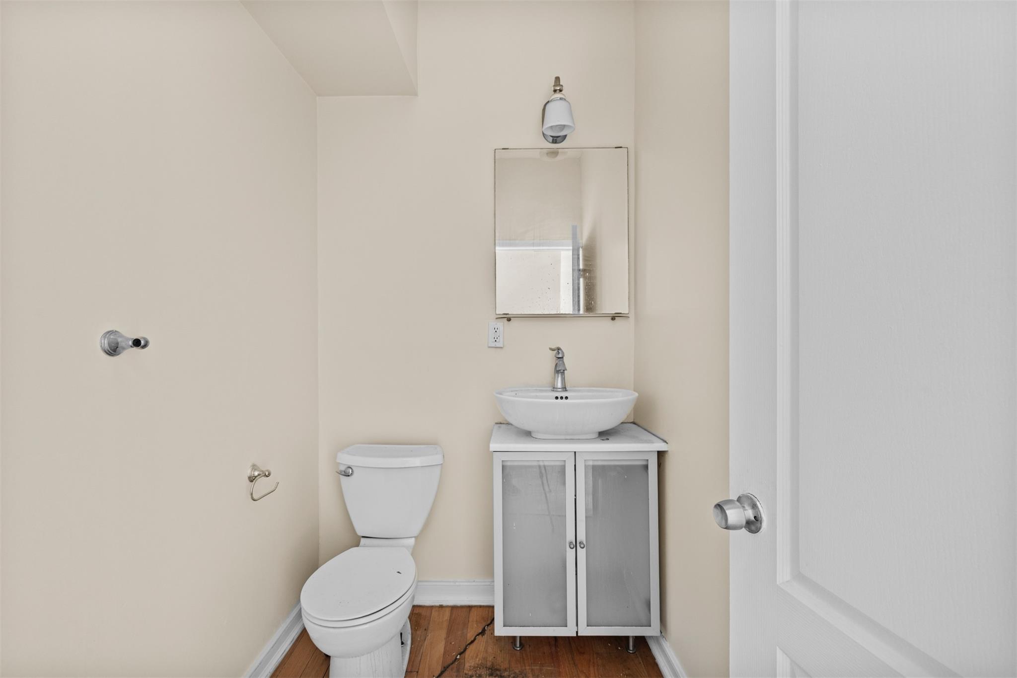 626 Madison Street Brooklyn, NY 11221 - Photo 24 of 42 Half bathroom featuring vanity, wood finished floors, toilet, and baseboards