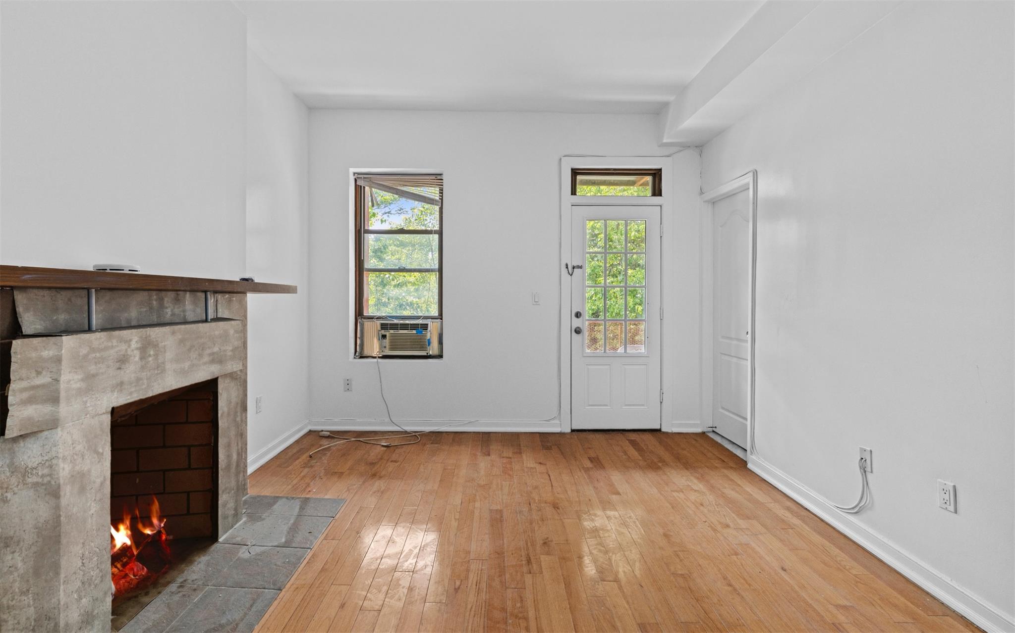 626 Madison Street Brooklyn, NY 11221 - Photo 26 of 42 Unfurnished living room with a tiled fireplace, hardwood / wood-style floors, and baseboards