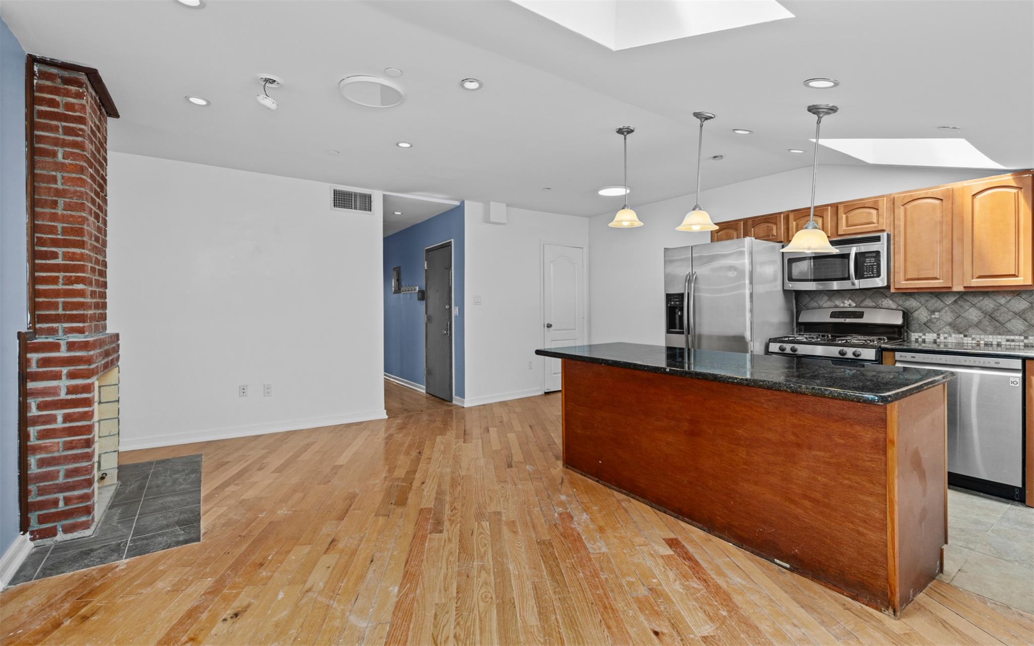 626 Madison Street Brooklyn, NY 11221 - Photo 30 of 42 Kitchen featuring appliances with stainless steel finishes, a skylight, light wood finished floors, a center island, and dark stone countertops