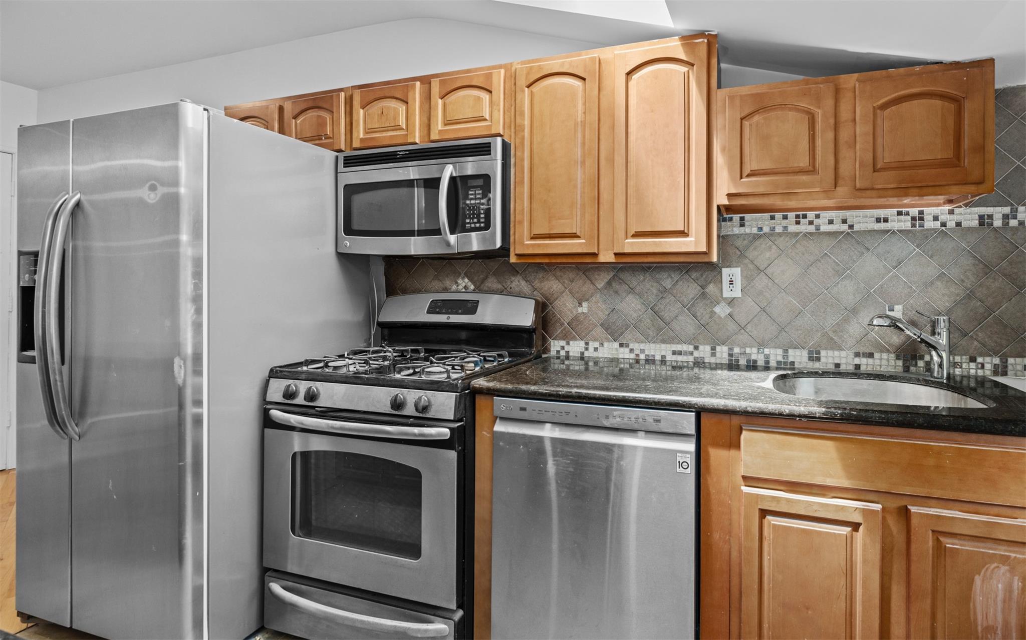 626 Madison Street Brooklyn, NY 11221 - Photo 32 of 42 Kitchen featuring appliances with stainless steel finishes, a sink, backsplash, and dark stone counters