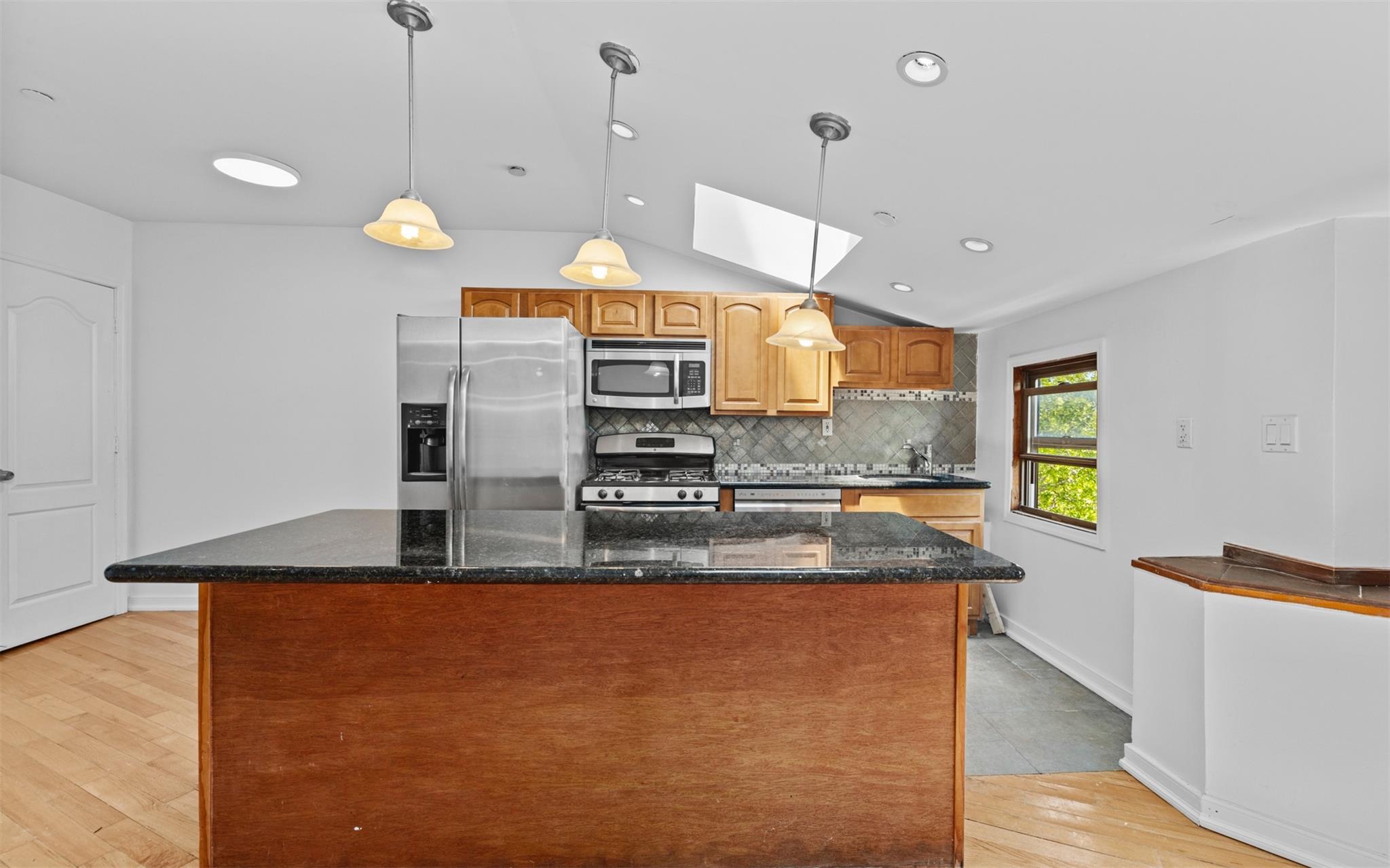 626 Madison Street Brooklyn, NY 11221 - Photo 33 of 42 Kitchen with appliances with stainless steel finishes, a skylight, lofted ceiling, a kitchen island, and light wood-style flooring