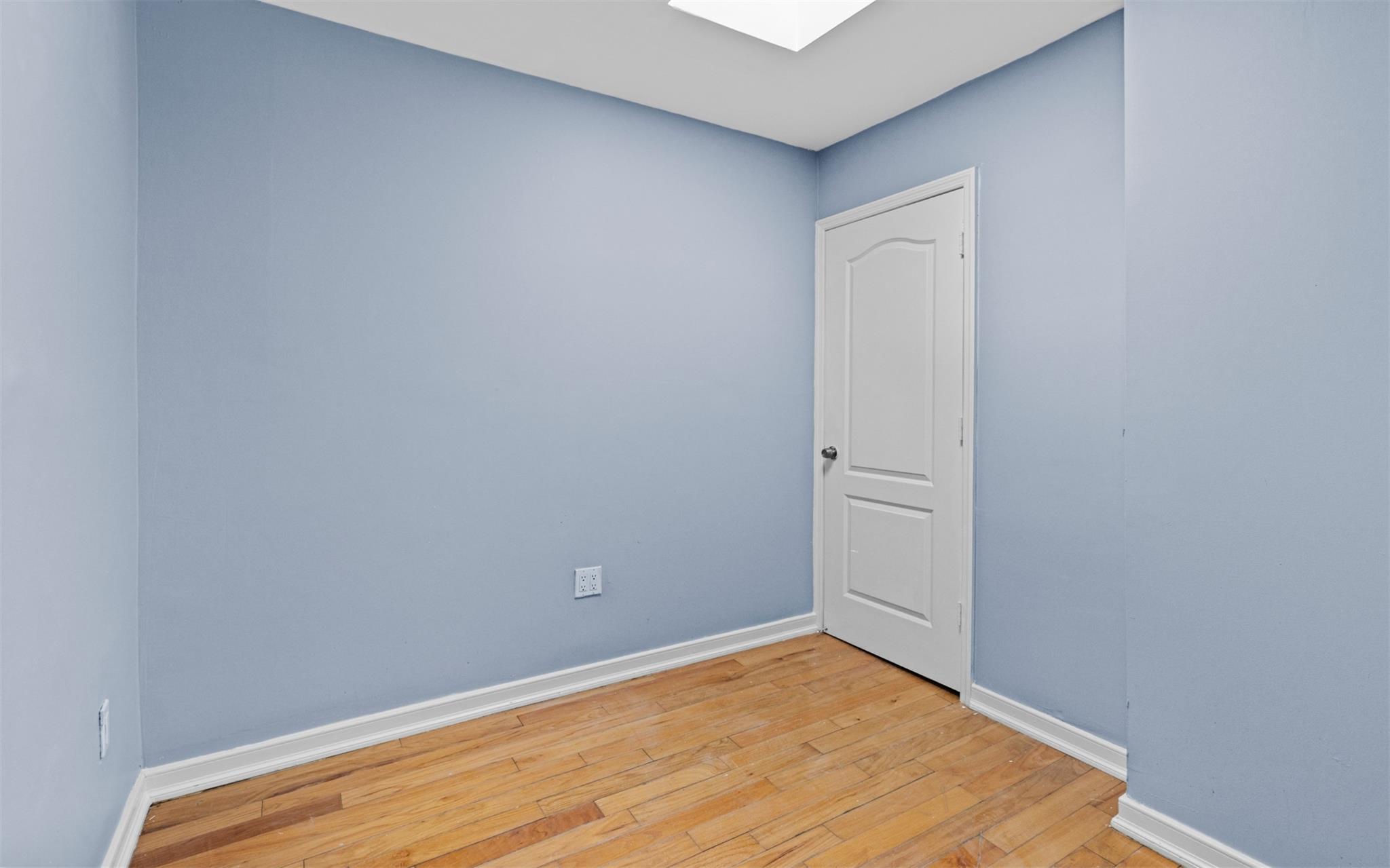 626 Madison Street Brooklyn, NY 11221 - Photo 34 of 42 Empty room with light wood finished floors, baseboards, and a skylight