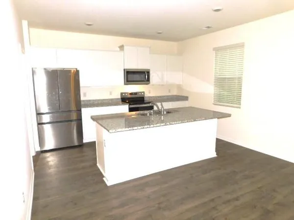 a kitchen with stainless steel appliances granite countertop a refrigerator a stove a sink and a microwave