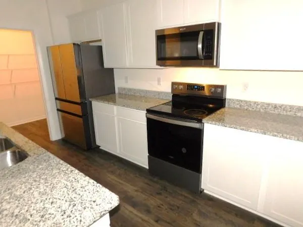 a kitchen with stainless steel appliances kitchen island granite countertop a refrigerator and a stove top oven