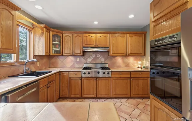 a kitchen with stainless steel appliances granite countertop a stove a sink and a refrigerator